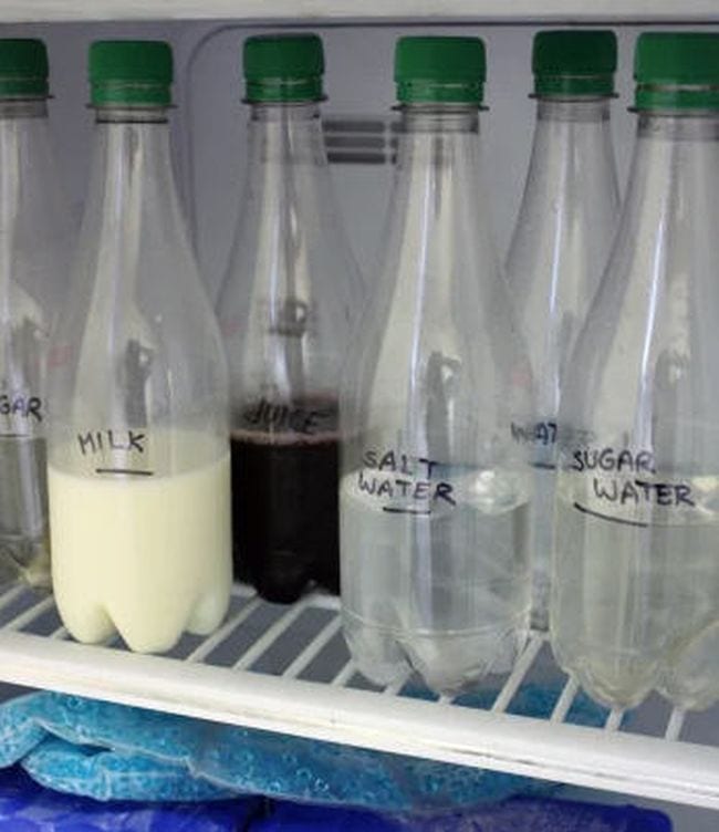 Freezing Liquids Experiment Clear bottles on a freezer shelf labeled milk, juice, salt water, water, and sugar water