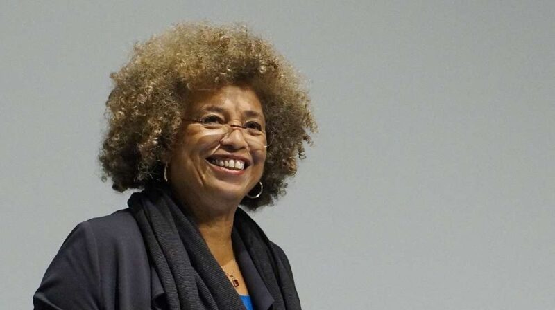 Angela_Davis A woman is seen in a modern color photograph smiling from the mid chest up.