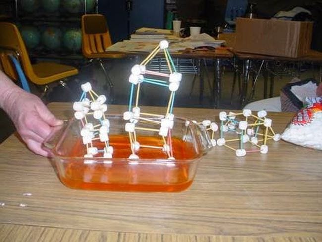 Fourth Grade Science Earthquake Simulation Fourth grade science teacher's hand shaking a pan of Jello topped with a house model made of toothpicks and marshmallows