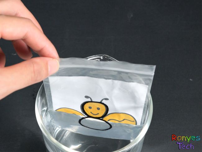 Fourth Grade Science: Light Refraction Student dipping a drawing into a glass of water, using light refraction to make the color disappear